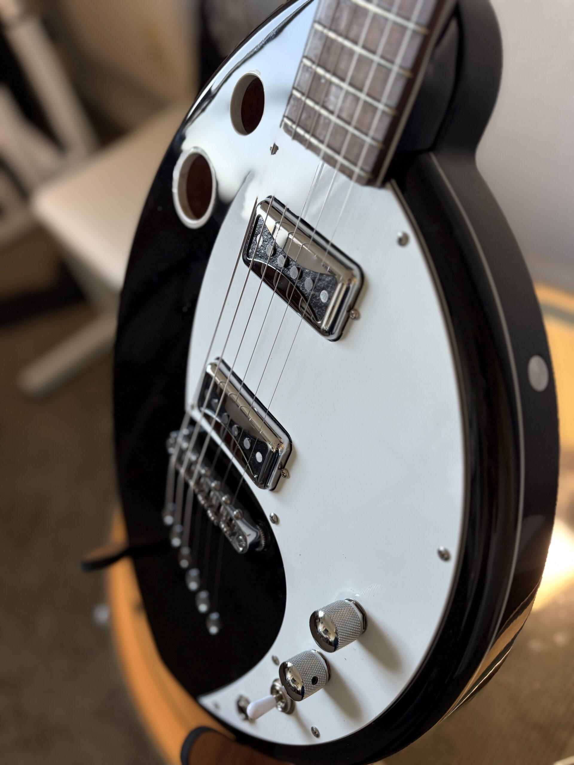 Black electric guitar with white pickguard, dramatic angle