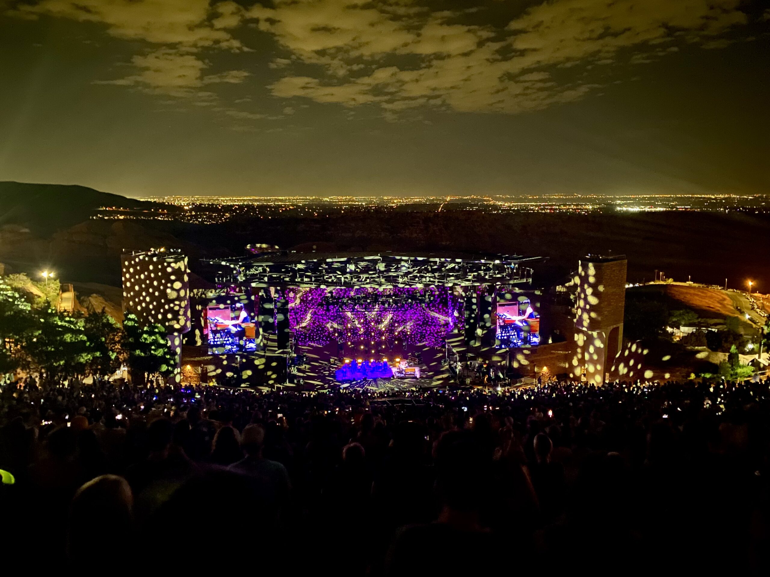 Concert at Red Rocks Amphitheatre at night with a large crowd and dotted stage lights